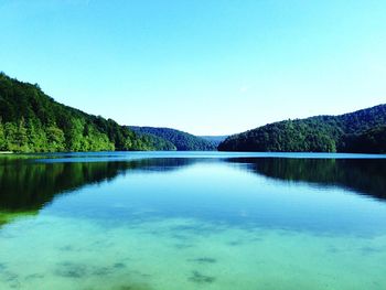 Scenic view of lake and mountains against clear blue sky