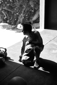 Shirtless fit young man working out at indoors garage-gym