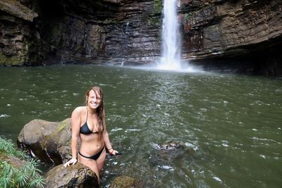 Portrait of young woman in bikini standing on rock