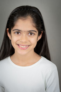 Portrait of smiling young woman against wall