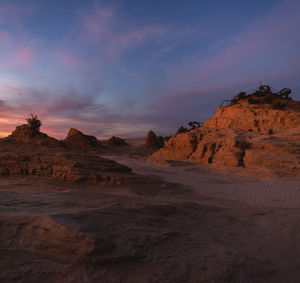 Rock formations on landscape against sky during sunset