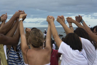 Rear view of people at beach against sky