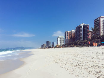 Panoramic view of beach and buildings against blue sky