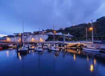 Sailboats moored in harbor at night