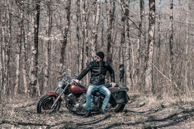 Mid adult man sitting on motorcycle in forest