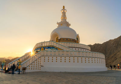 Group of people at temple against sky during sunset