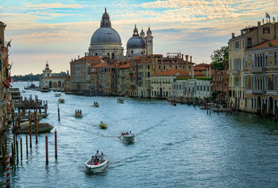 Boats in canal amidst buildings against sky