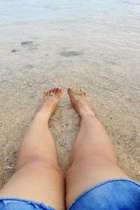 Low section of woman relaxing on beach