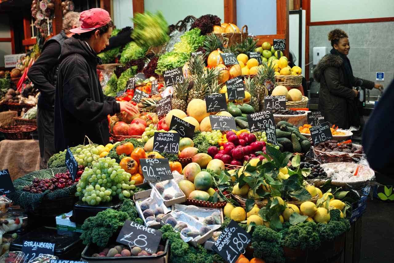 food and drink, men, lifestyles, retail, for sale, freshness, food, market, healthy eating, market stall, standing, vegetable, casual clothing, fruit, person, leisure activity, abundance, variation