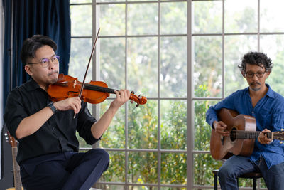 Two musician practice playing guitar and violin together