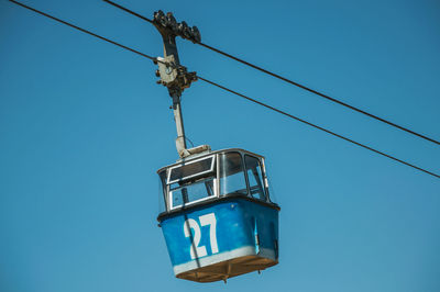 Low angle view of telephone pole against clear blue sky