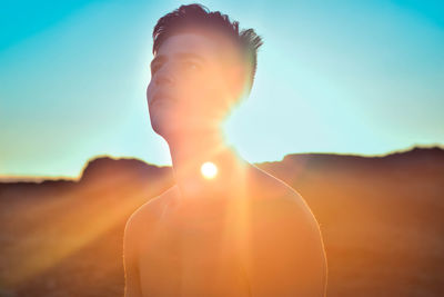 Shirtless man against sky during sunset