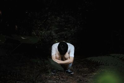 Woman sitting in forest at night