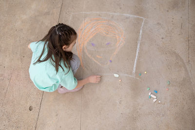 Girl draws with colorful crayons on pavement. children's drawings with chalk on wall. creative kid. 