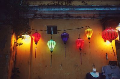 Low angle view of illuminated lanterns hanging by building