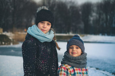 Portrait of cute siblings standing on snow