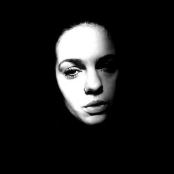 Close-up portrait of young woman against black background