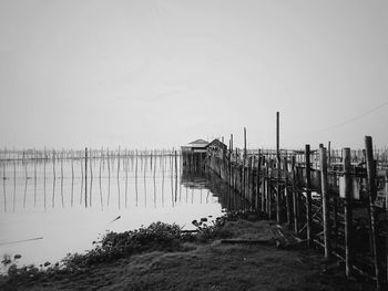 Wooden posts in sea against clear sky