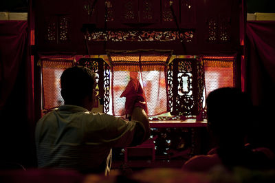 Rear view of people sitting in temple
