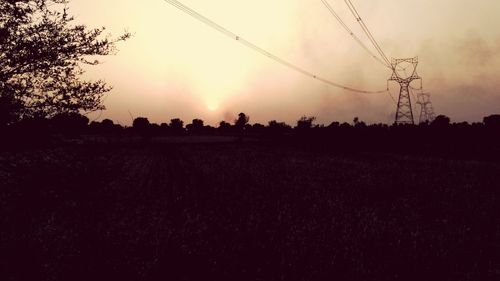 Silhouette trees on field against sky during sunset