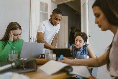 Young man studying with female friends at home