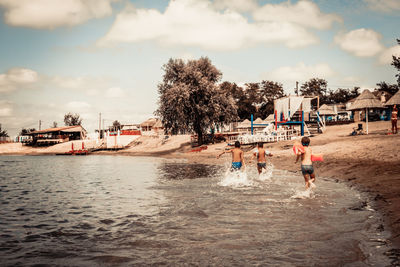 Rear view of kids running through water in summer day.