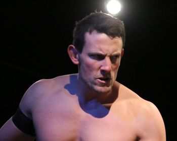 Portrait of shirtless man against black background