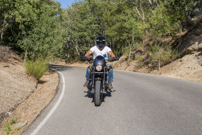 Young man riding motorcycle on road