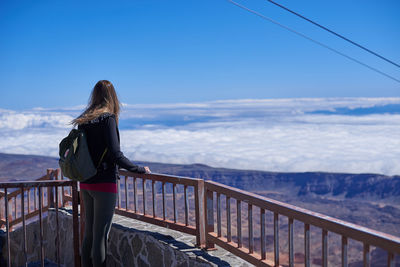 Woman standing by railing against sky