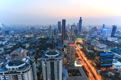 Illuminated cityscape against sky at dusk