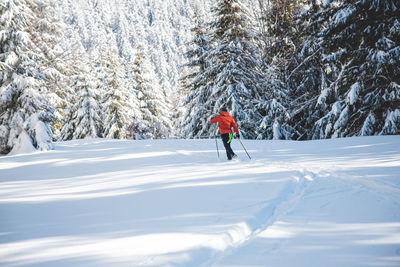 Rear view of man skiing on snow covered field