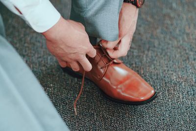 Low section of man tying shoelace