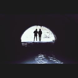 Silhouette people in illuminated tunnel