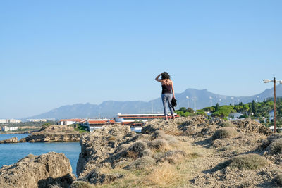 Woman looking at sea against clear blue sky