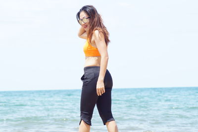 Full length of woman standing by sea against sky