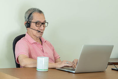 Portrait of man using mobile phone while sitting on table