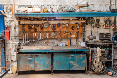 Old collection of various repair tools hangs on wall above table. workshop with tools.