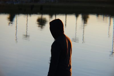 Rear view of silhouette man standing in lake