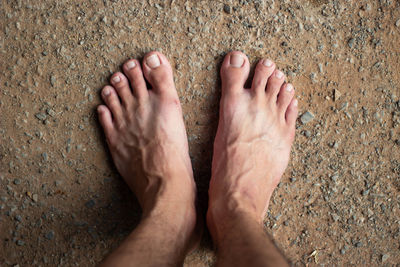 Low section of man standing on sand
