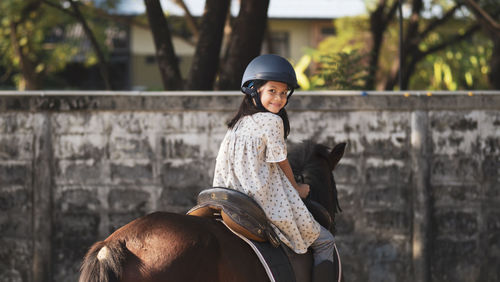 Asian shool kid girl with horse ,riding or practicing horse ridding at horse ranch.