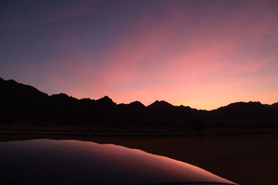 Scenic view of silhouette mountains against romantic sky at sunset