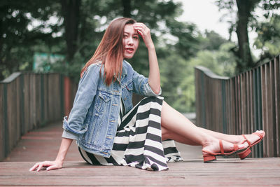 Portrait of beautiful woman sitting on footbridge