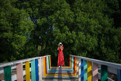 Woman standing by railing against trees