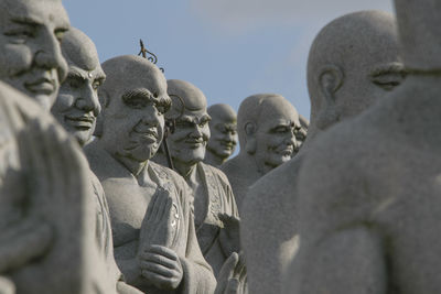 Close-up of buddha statues against sky