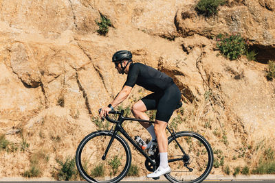 Rear view of man riding bicycle on mountain