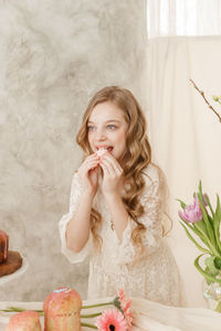 A girl with long hair in a light dress is sitting at the easter table. happy easter celebration.