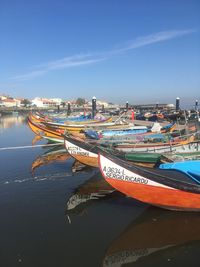 Boats moored at harbor against blue sky