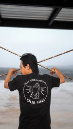 Man holding camera while standing against sky