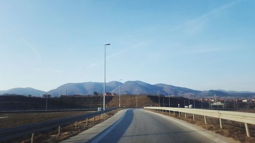 Road leading towards mountain against sky