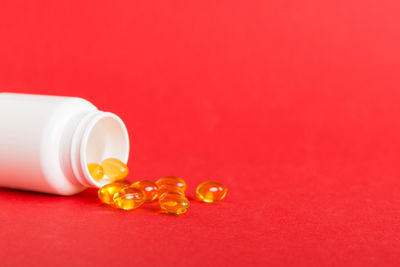 Pills spilling from bottle on yellow background